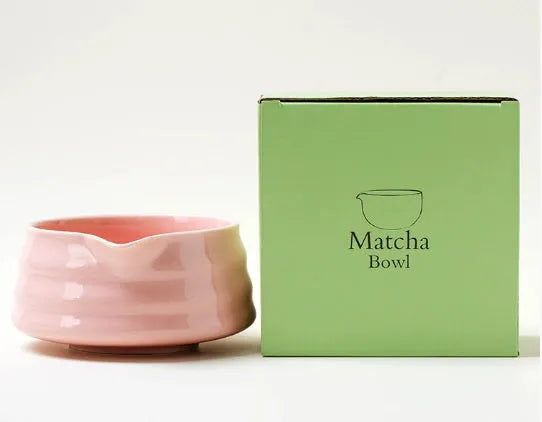 Ceramic matte tea whisk stand in bright white holding a bamboo matcha whisk upright on a wooden tray