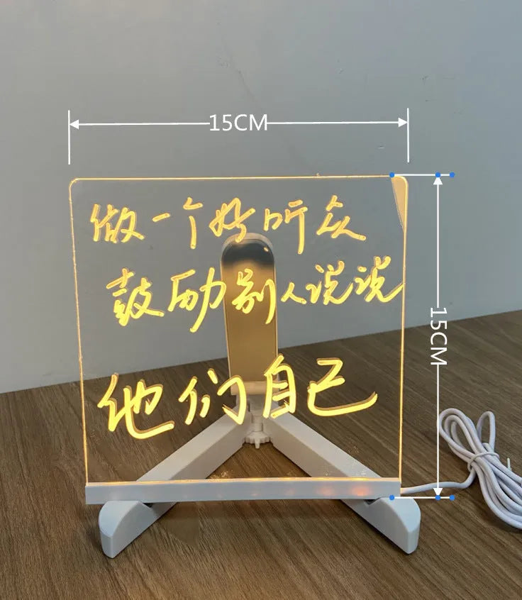 Acrylic DIY LED message board on a bracket, glowing softly with handwritten notes, alongside white and colourful pens.