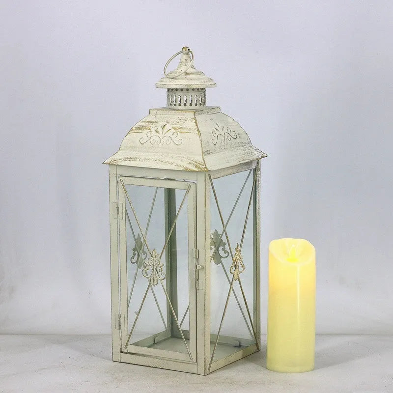 Black wrought iron floor-standing storm lantern with clear tempered glass panels on a garden patio.