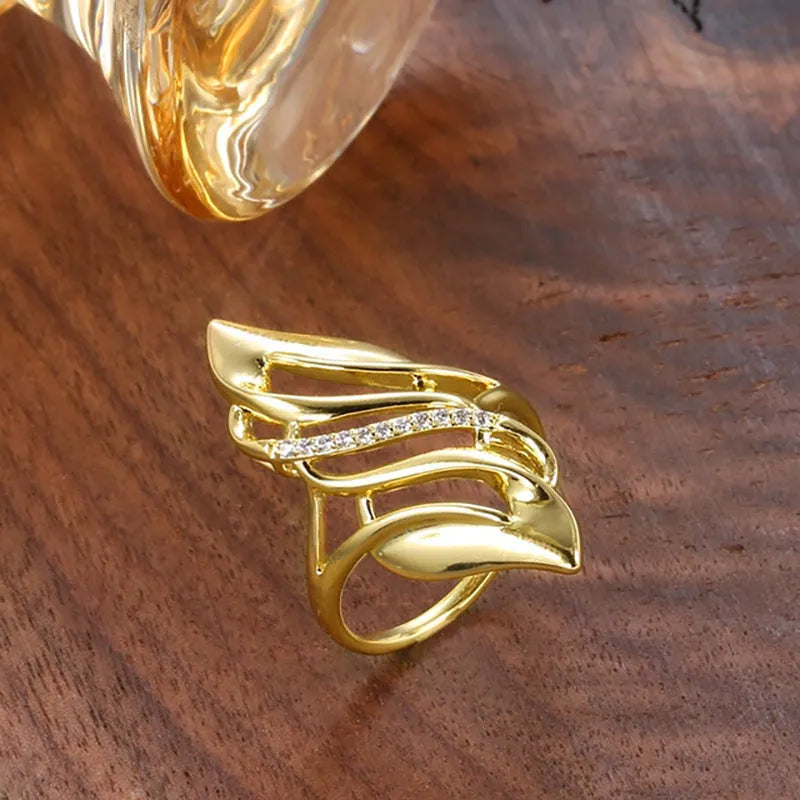 Gold women's ring with exaggerated curved design on a copper band, shown in casual style.