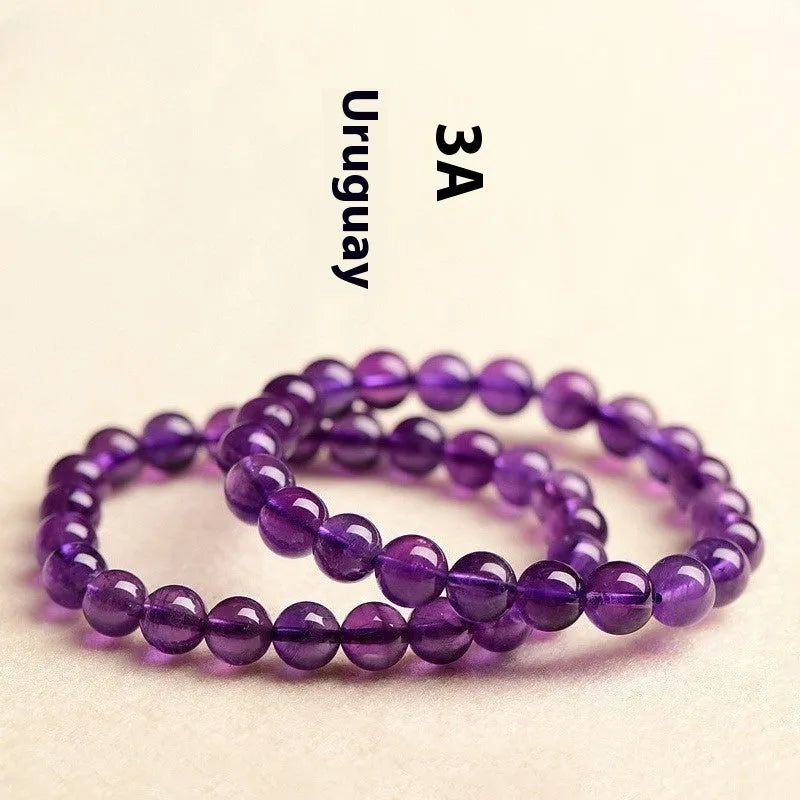 Close-up of a polished natural amethyst bead bracelet with a sliding knot closure on a wrist.