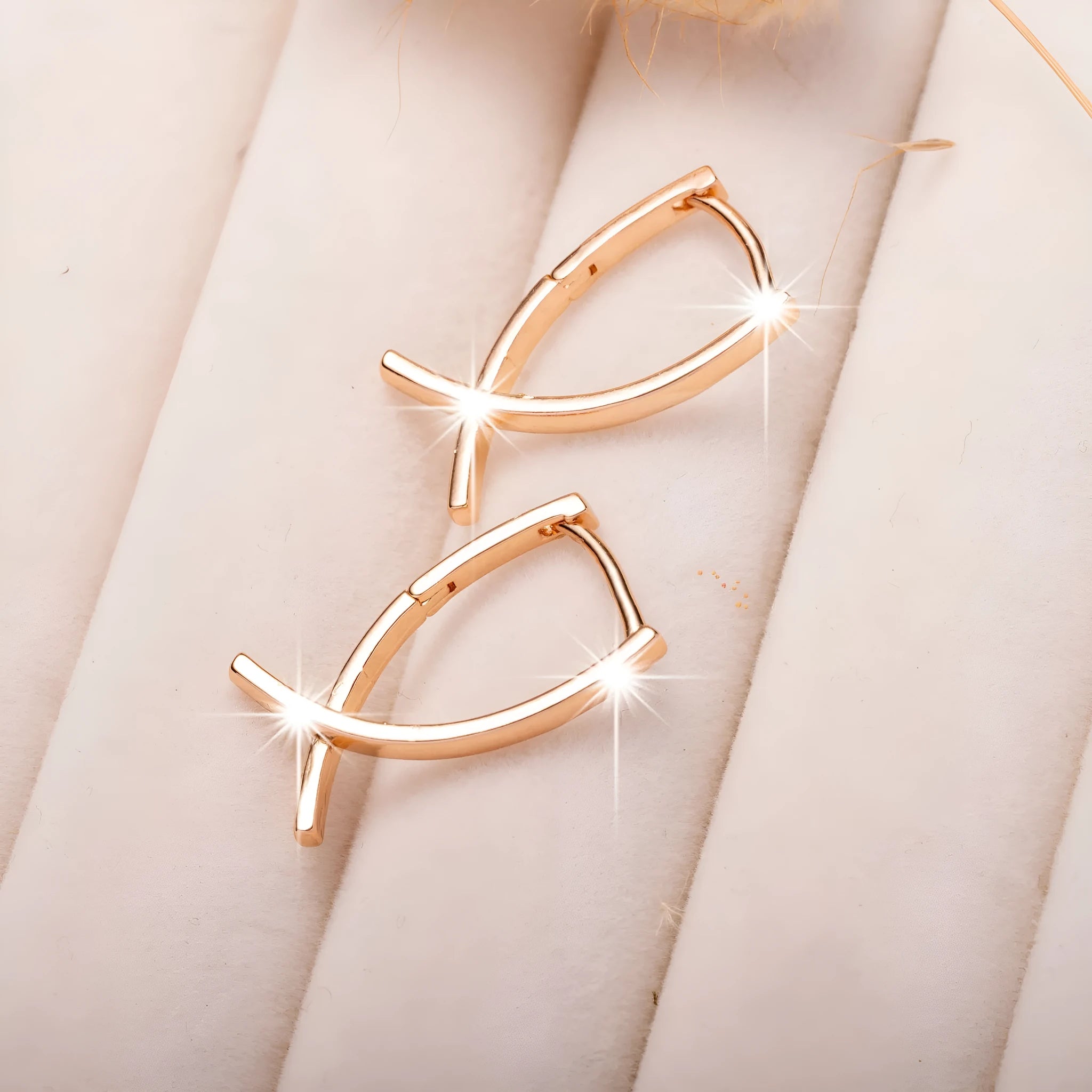 Close-up of a pair of rose gold cross drop earrings on a white background, showing post fittings.