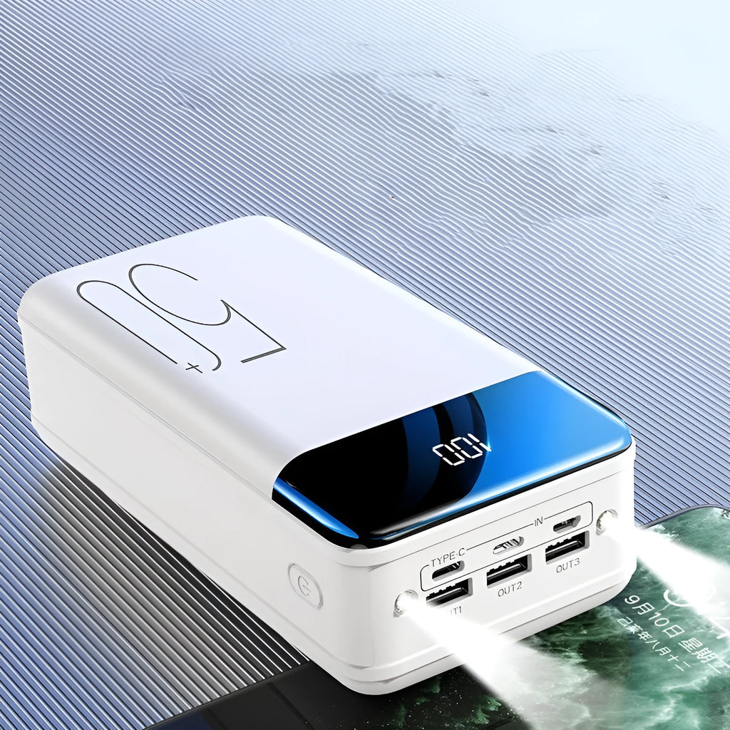Black and white large 50,000mAh portable power bank with three output ports on a table.
