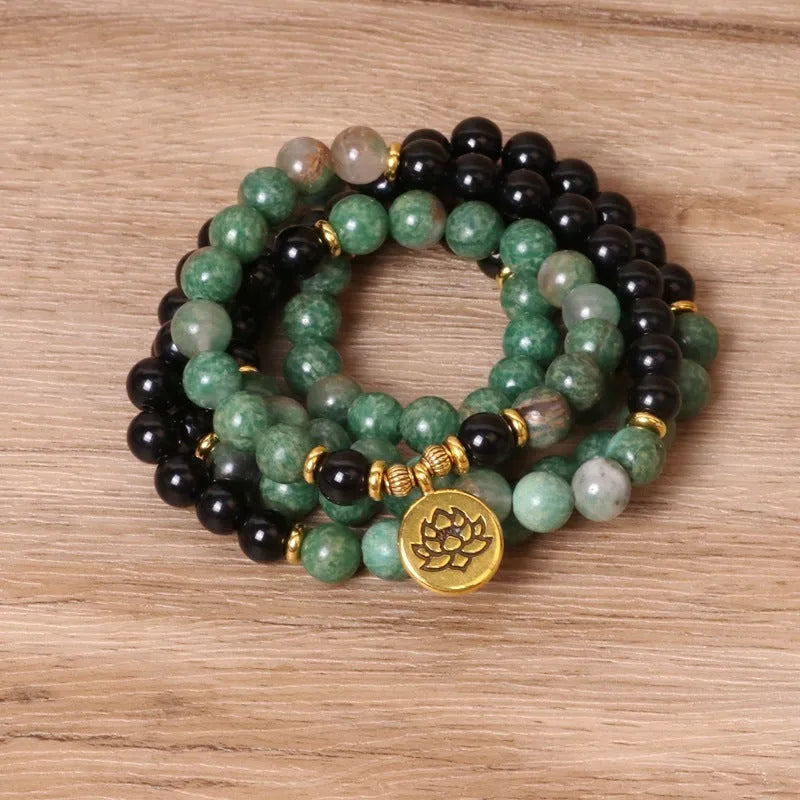 Green and black alloy bead long bracelet with elasticated band on a wrist.