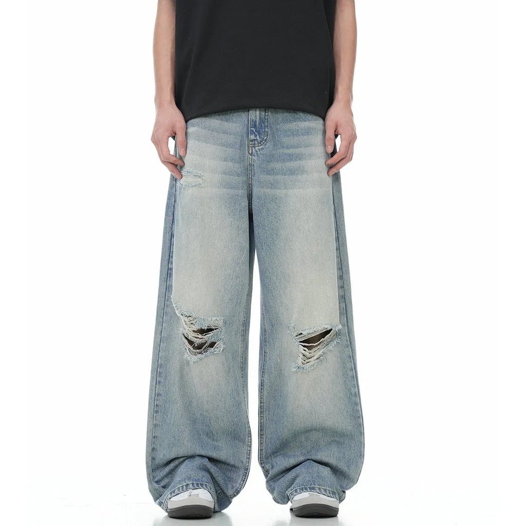 Blue men's straight-leg jeans with ripped details and a zip fly on a neutral background.
