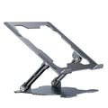Grey aluminium folding laptop stand shown at an adjustable angle on a wooden desk.