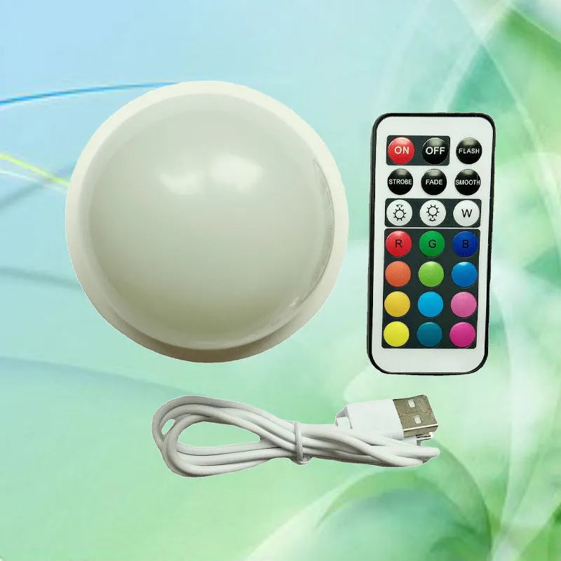Compact colourful gradient 3D shooting night light with remote control on a desk.