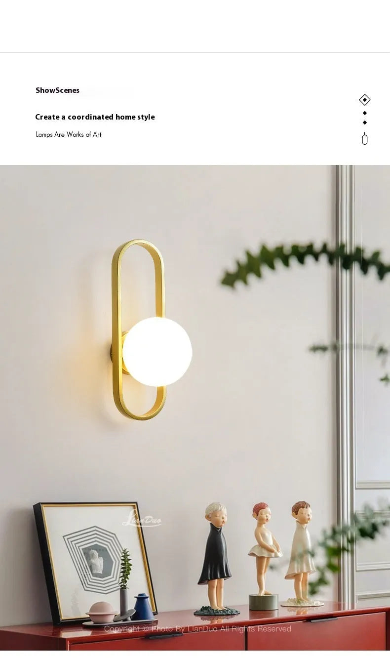 Modern minimalist wall lamp with black iron arm and clear glass shade, mounted on a plain wall.