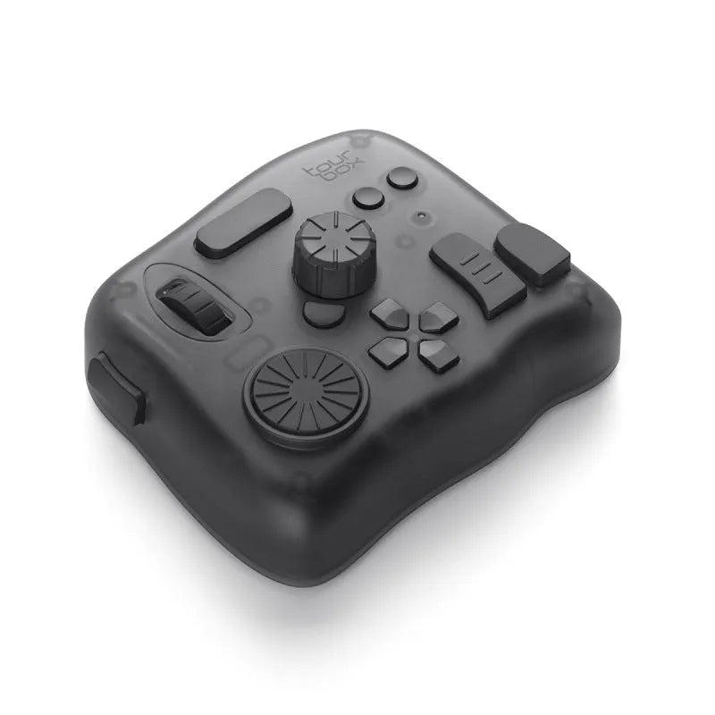 TourBox NEO black video editing controller with dials and buttons on a desk next to a tablet.