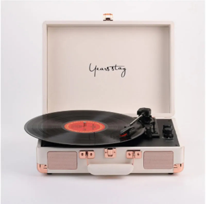 A black leather case Bluetooth turntable for vinyl and film records on a wooden surface.