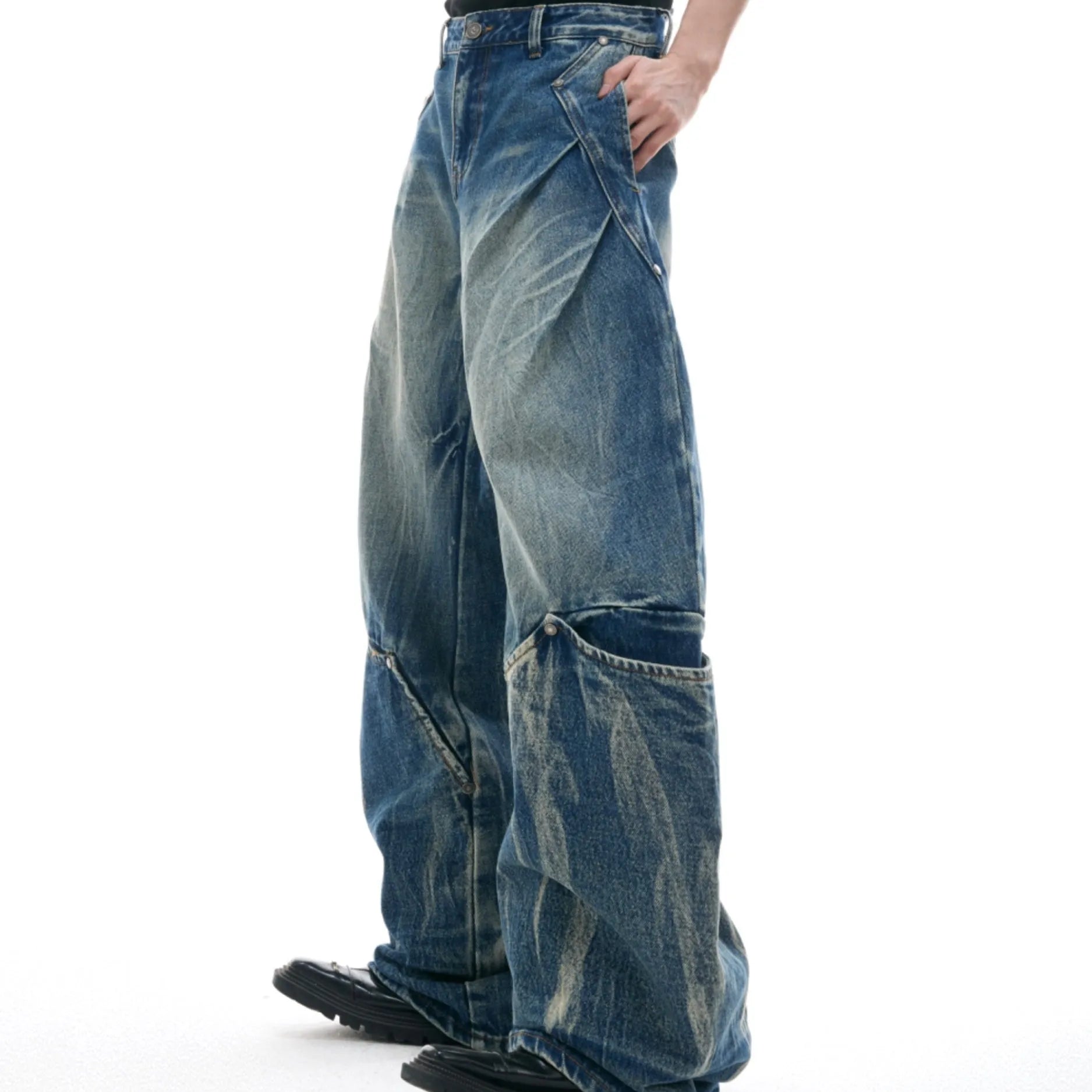 Man wearing verdant blue loose-fit retro jeans with a curved knife washed pattern on the legs.