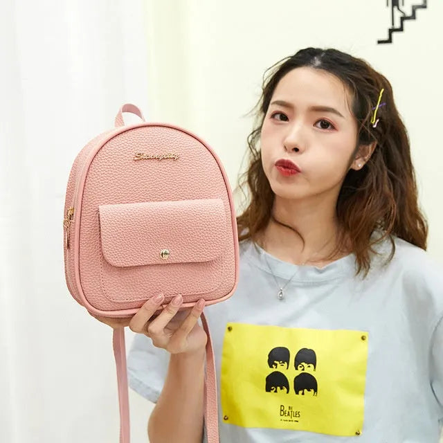 Small black PU women's backpack worn on shoulder, showing zip closure and compact size.