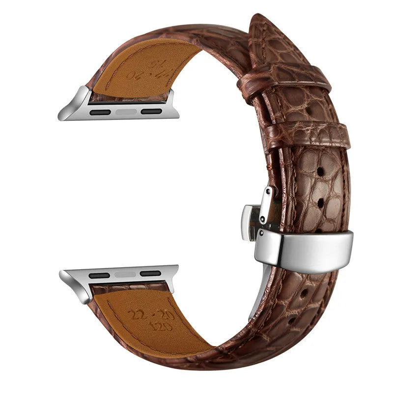 Genuine crocodile skin watch strap in brown with rose gold buckle, 42-44mm width, on a wooden surface