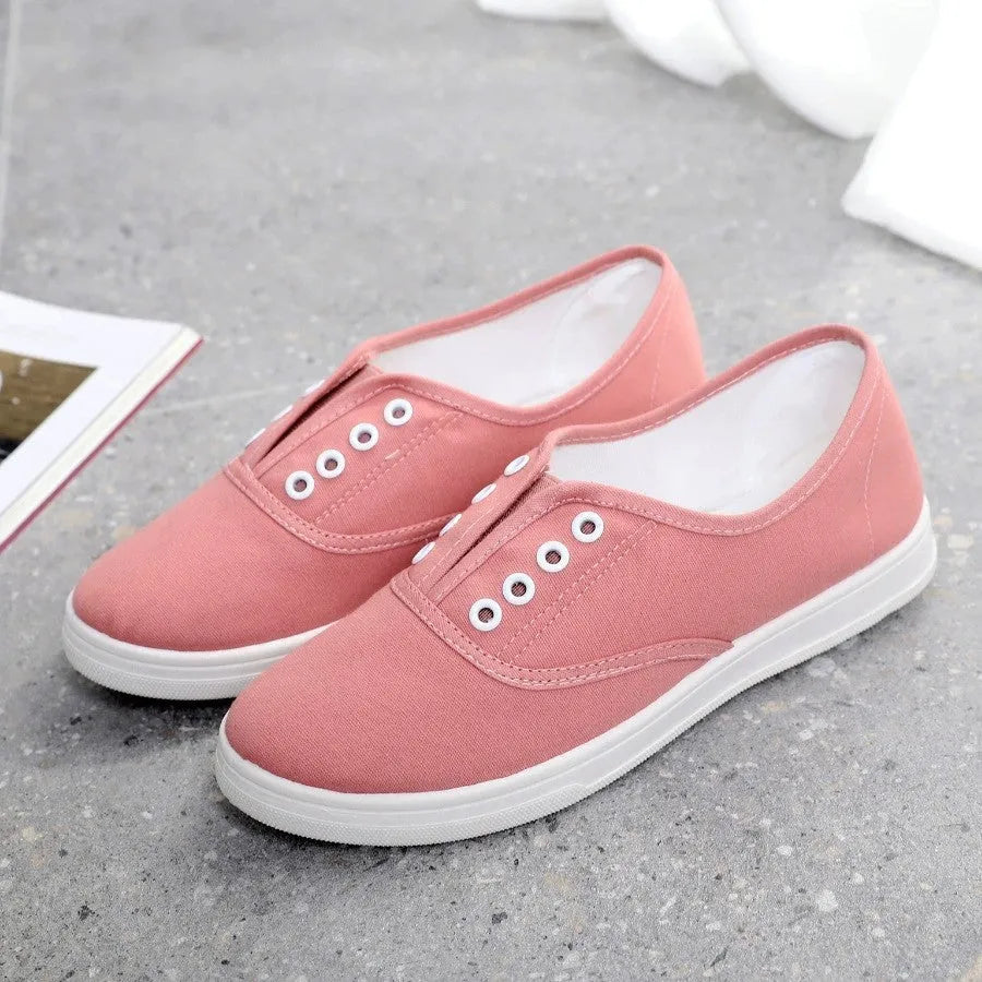Low-top casual canvas shoes on a flat heel, shown in various colours including black, white, grey, and pink.