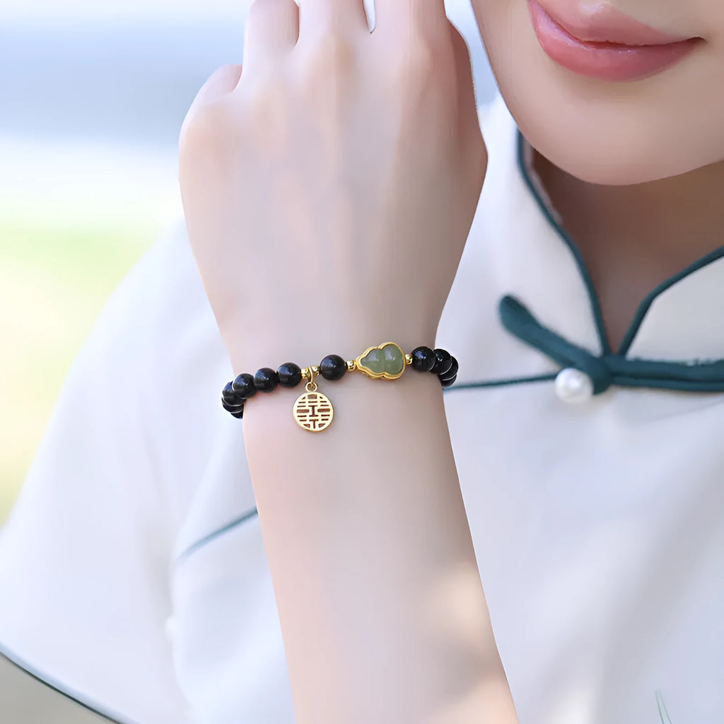 Black obsidian bracelet with a Hetian jade gourd charm, shown in couple style with geometric beads.