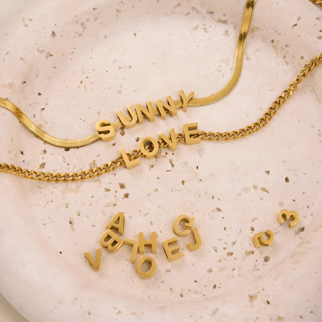 Gold and silver titanium steel necklaces with letter, number, and heart charms on a 40.5cm chain.