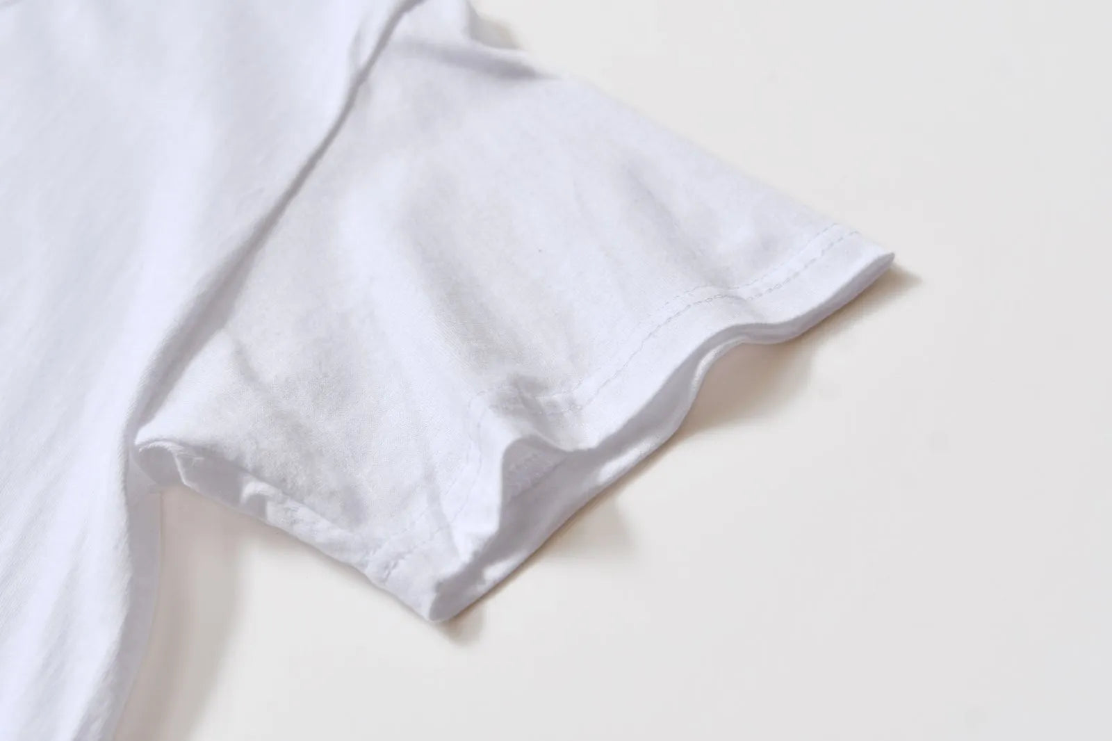 White cotton T-shirt overalls with a round neck and short sleeves, shown in a loose pullover style.