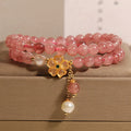 Women's double ring bracelet with strawberry quartz four-leaf clover charms on wrist.