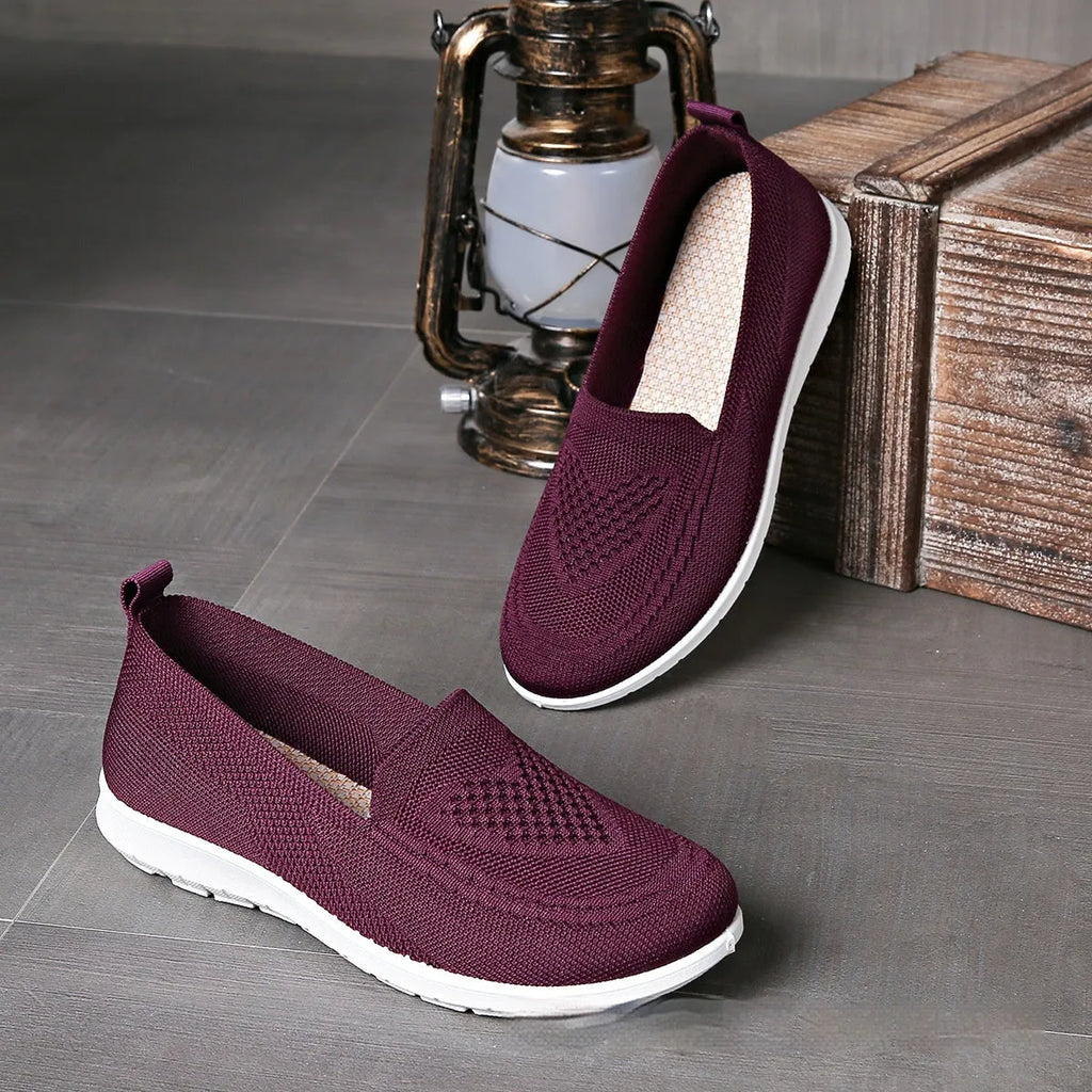 Women's beige canvas flat shoes with a heart pattern, mesh lining, and a flat rubber sole.