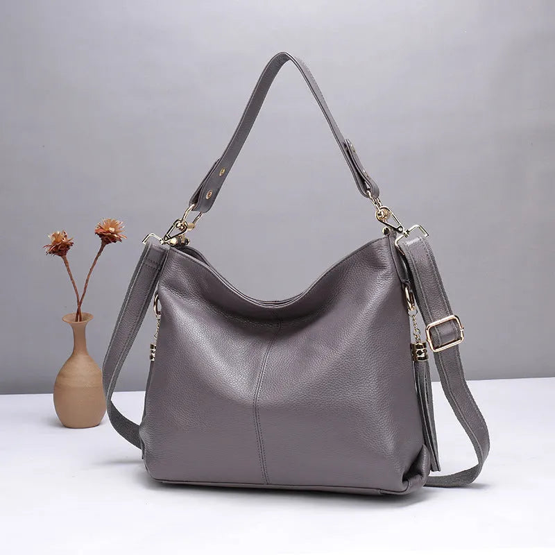 Genuine leather vertical square crossbody bag in black with sewing line detail and external pocket.