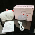 Sleepy cat shaped silicone induction night light with white glow on table