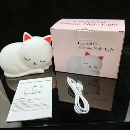 Sleepy cat shaped silicone induction night light with white glow on table