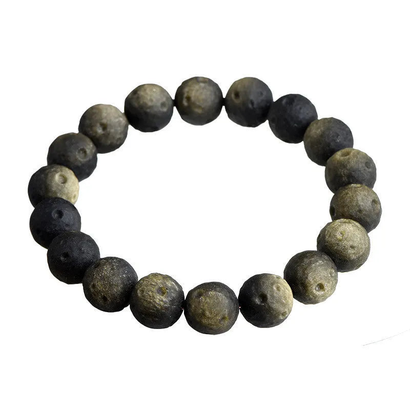 Close-up of an obsidian crater ball bead bracelet in a gold meteorite finish, showing its textured spherical beads.