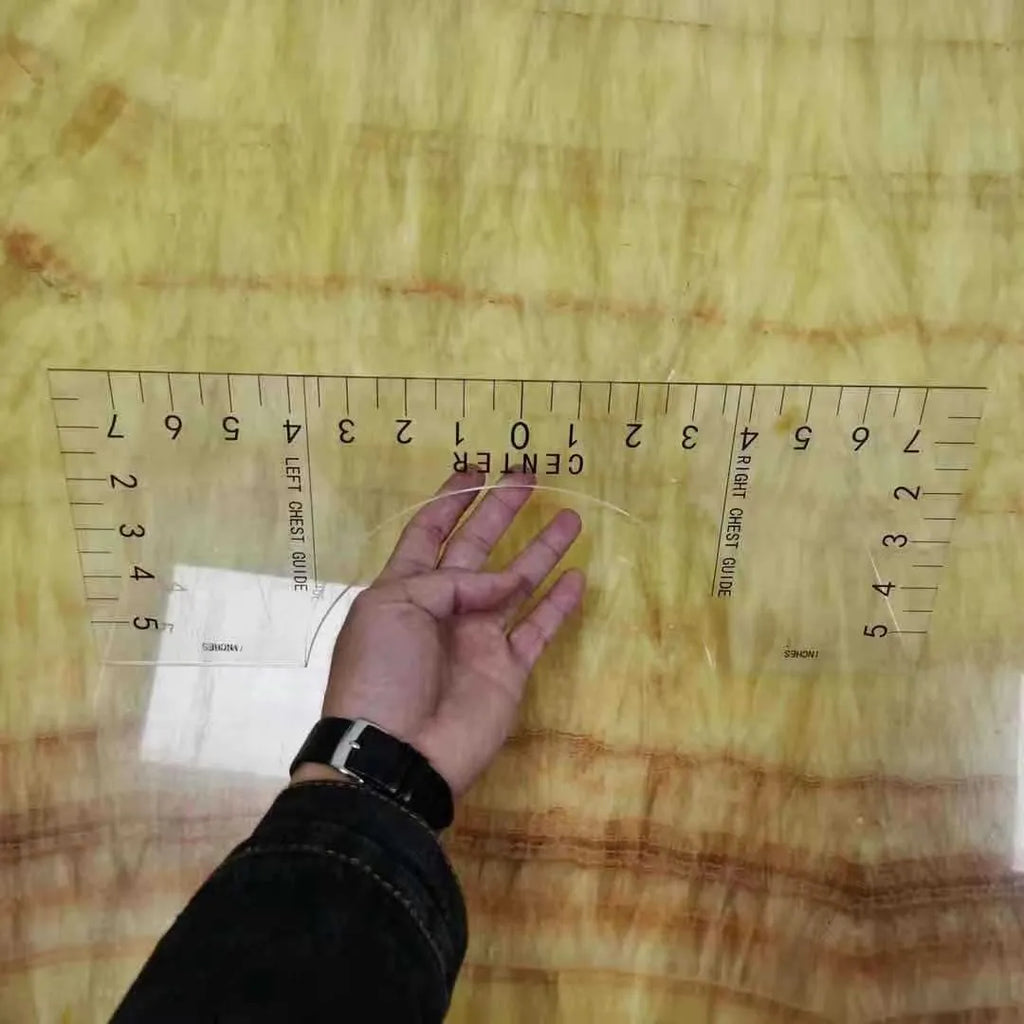 Transparent acrylic sewing ruler for T-shirt alignment and patch placement on fabric.
