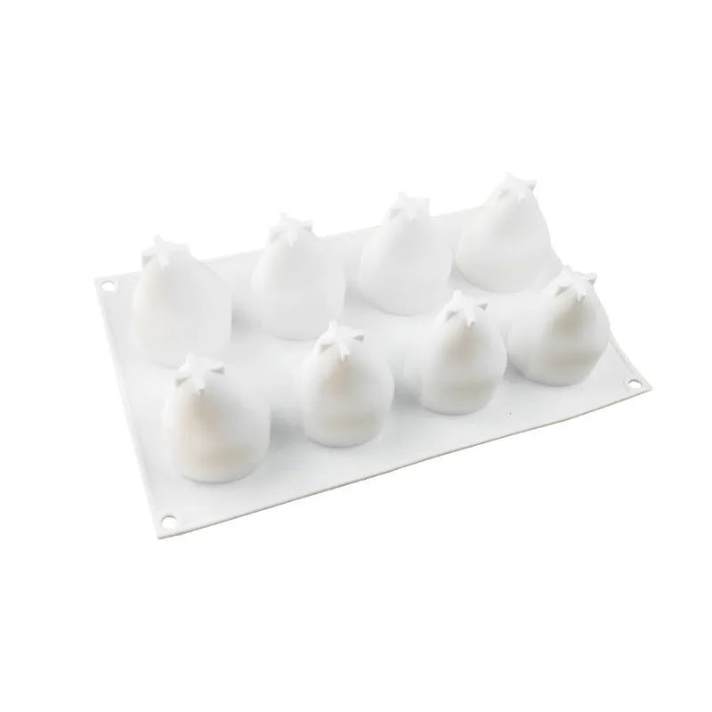 Set of six silicone baking moulds shaped as pineapples, pine cones, and pears on a kitchen counter.