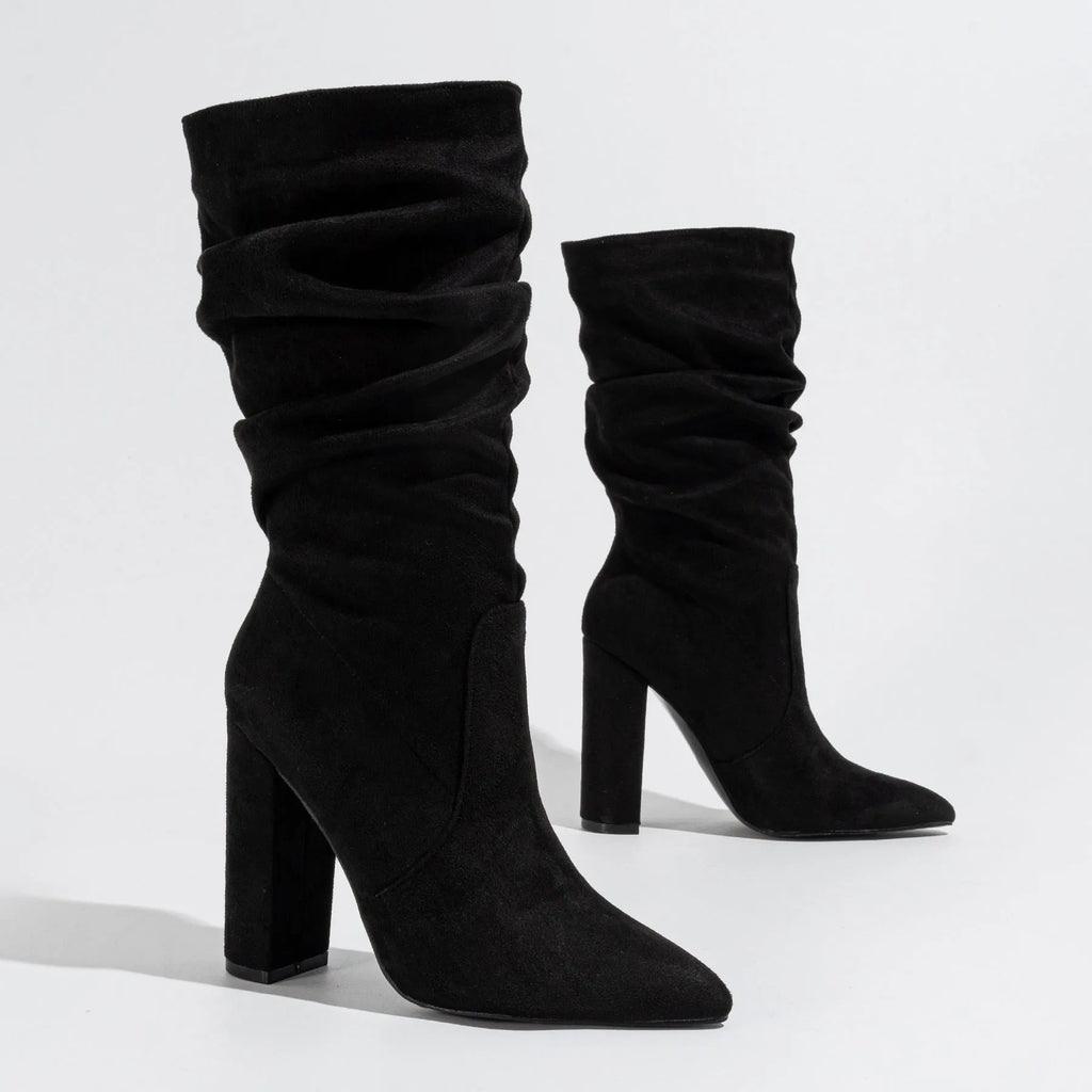 Black suede women's boots with a chunky high heel and pointed toe, shown on a middle calf.