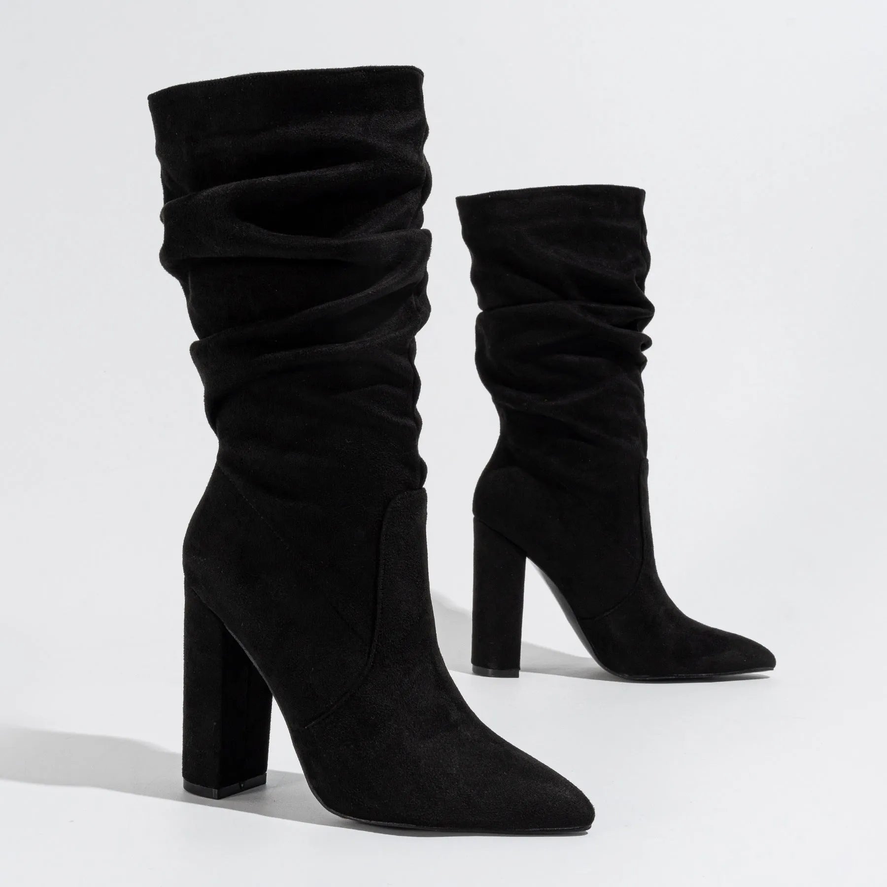 Black suede women's boots with a chunky high heel and pointed toe, shown on a middle calf.