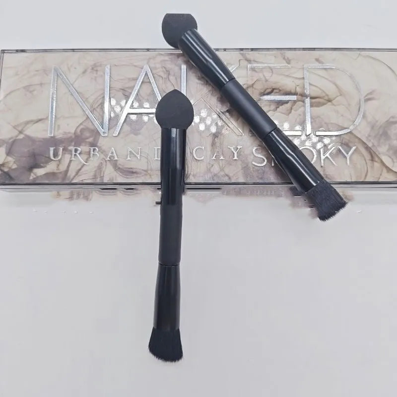 Black wooden handle concealer brush with a grey sponge tip applicator angled for under eye use.