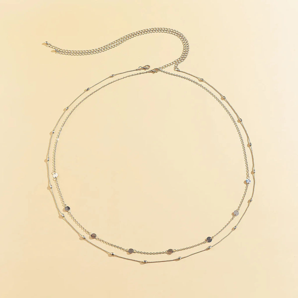 Gold double-layer belly chain with tassel detail and lobster clasp on a white background
