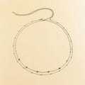 Gold double-layer belly chain with tassel detail and lobster clasp on a white background