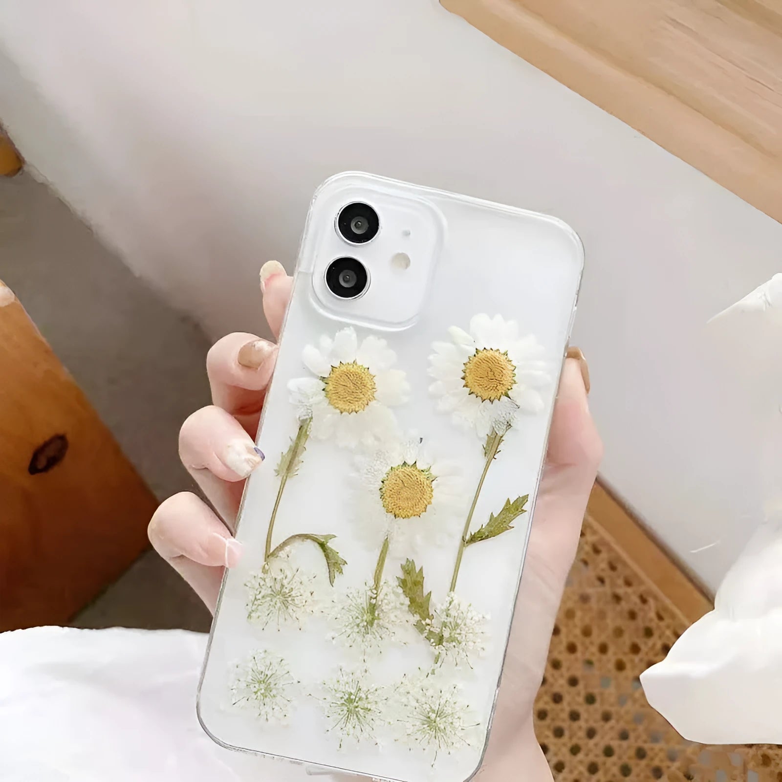 White iPhone case with a raised epoxy daisy floral pattern on the back.