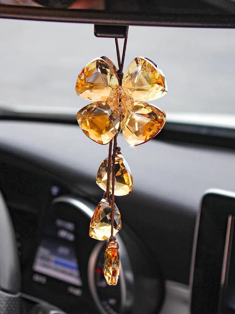 Crystal four leaf clover car pendant hanging, shown in one of four colour options: transparent, champagne, translucent black, or extremely shiny.
