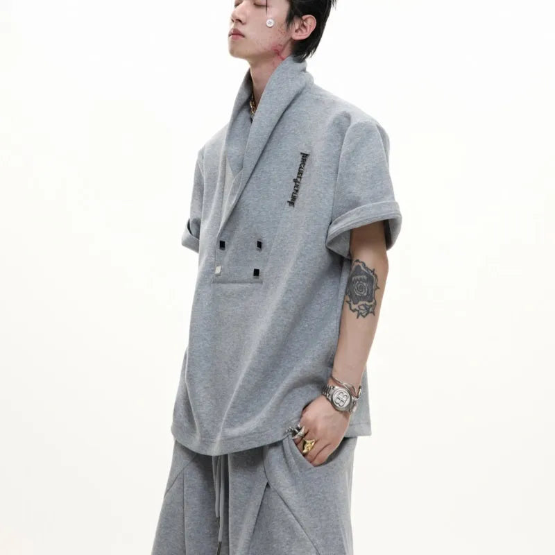 Men's dark grey V-neck sports suit with padded shoulders, metal details, and cotton shorts laid flat.