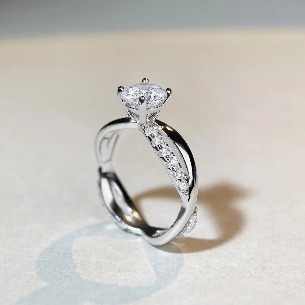 Geometric twisted silver band ring with a 1 carat round moissanite stone in a four-claw setting.