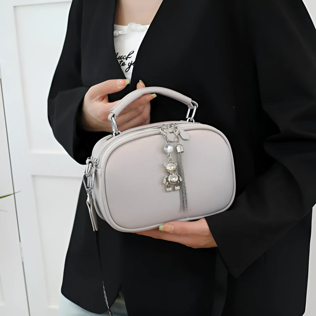 Oval-shaped women's small square handbag in PU with stitching detail and double straps.