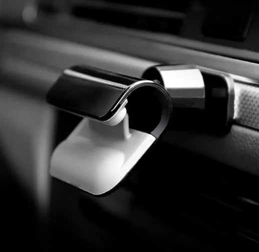 Black universal car phone holder mounted on dashboard with phone inserted showing 360-degree rotation