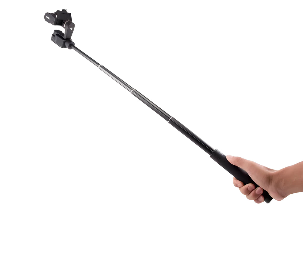 Black retractable aluminium selfie stick extended in hand next to a smartphone.