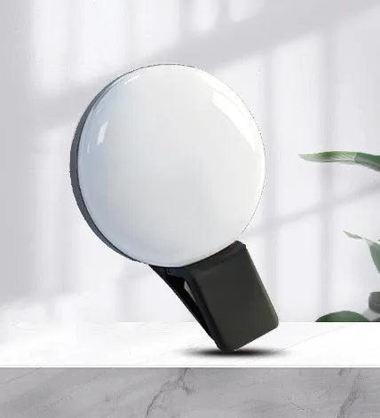 Round white mobile phone fill light clipped onto a smartphone for selfies.