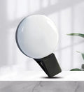 Round white mobile phone fill light clipped onto a smartphone for selfies.