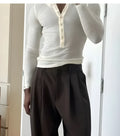 Men's cream-coloured ribbed long-sleeve henley top with button placket on a hanger.