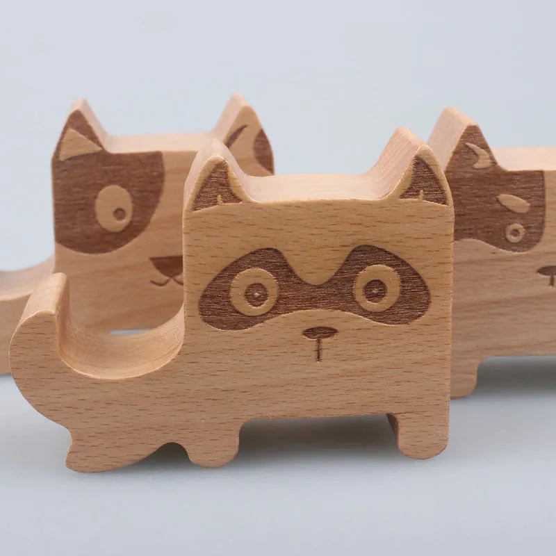 Sculpted beech wood lazy bracket phone holder with custom engraved text on a wooden desk.