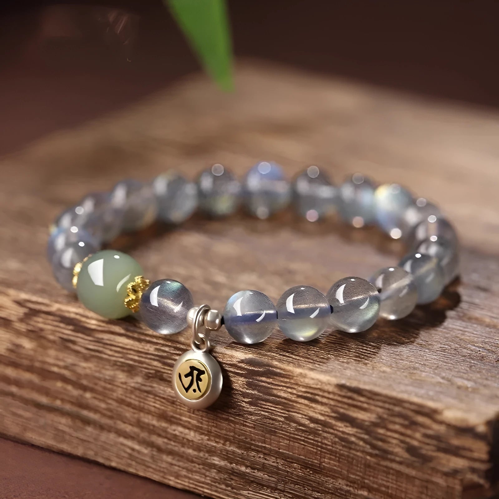 Moonstone bracelet with 8mm beads and a silver Guanyin mouse zodiac charm on a black background.