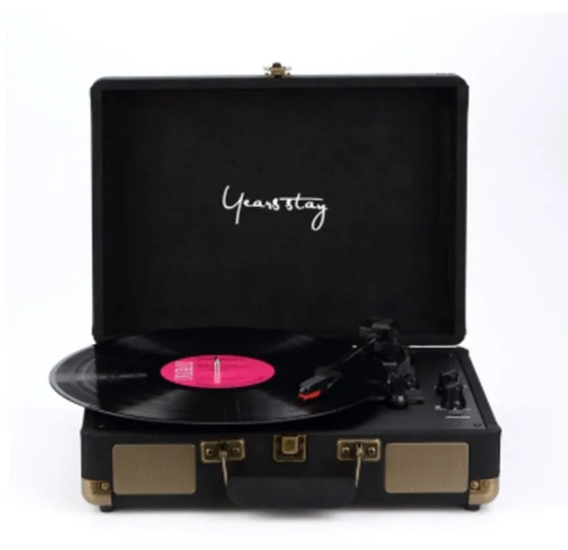 A black leather case Bluetooth turntable for vinyl and film records on a wooden surface.