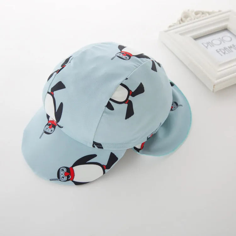 Boy's penguin print long sleeve swimsuit top and matching swim cap set on blue background