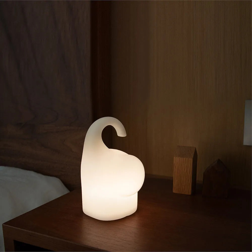 DOMI Elephant shaped silicone night light with warm white glow on a bedside table.