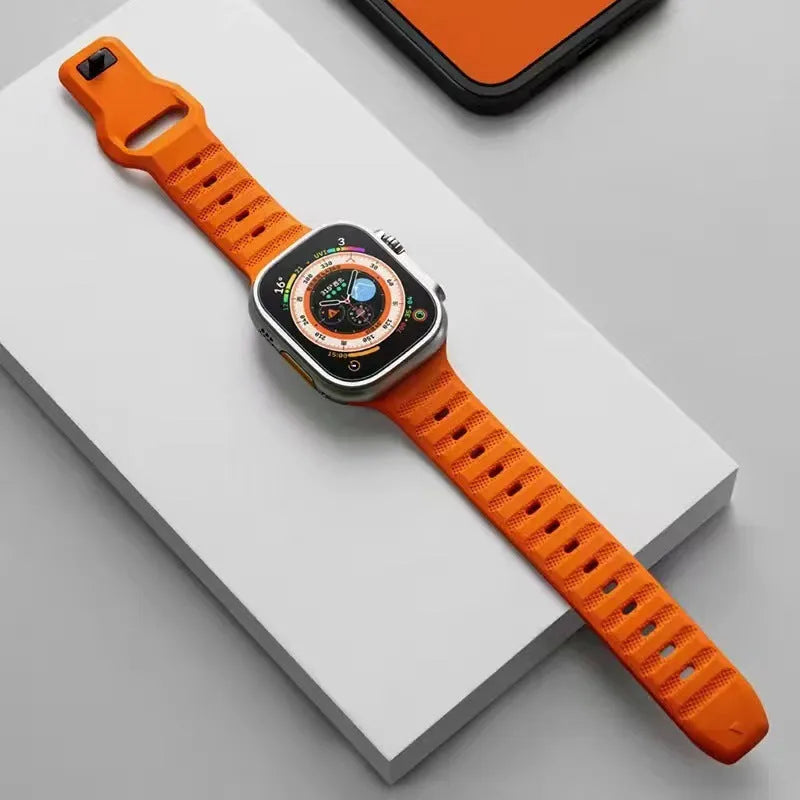 Black fluoro rubber Apple Watch band with T-buckle closure on a wrist, showing compatible Ultra model.